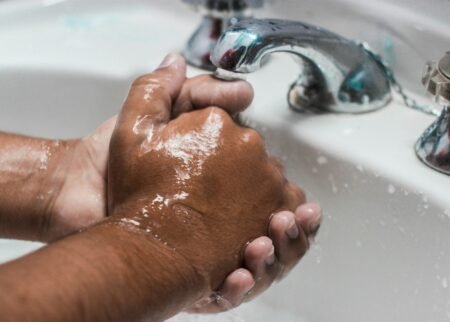 person washing hand on sink